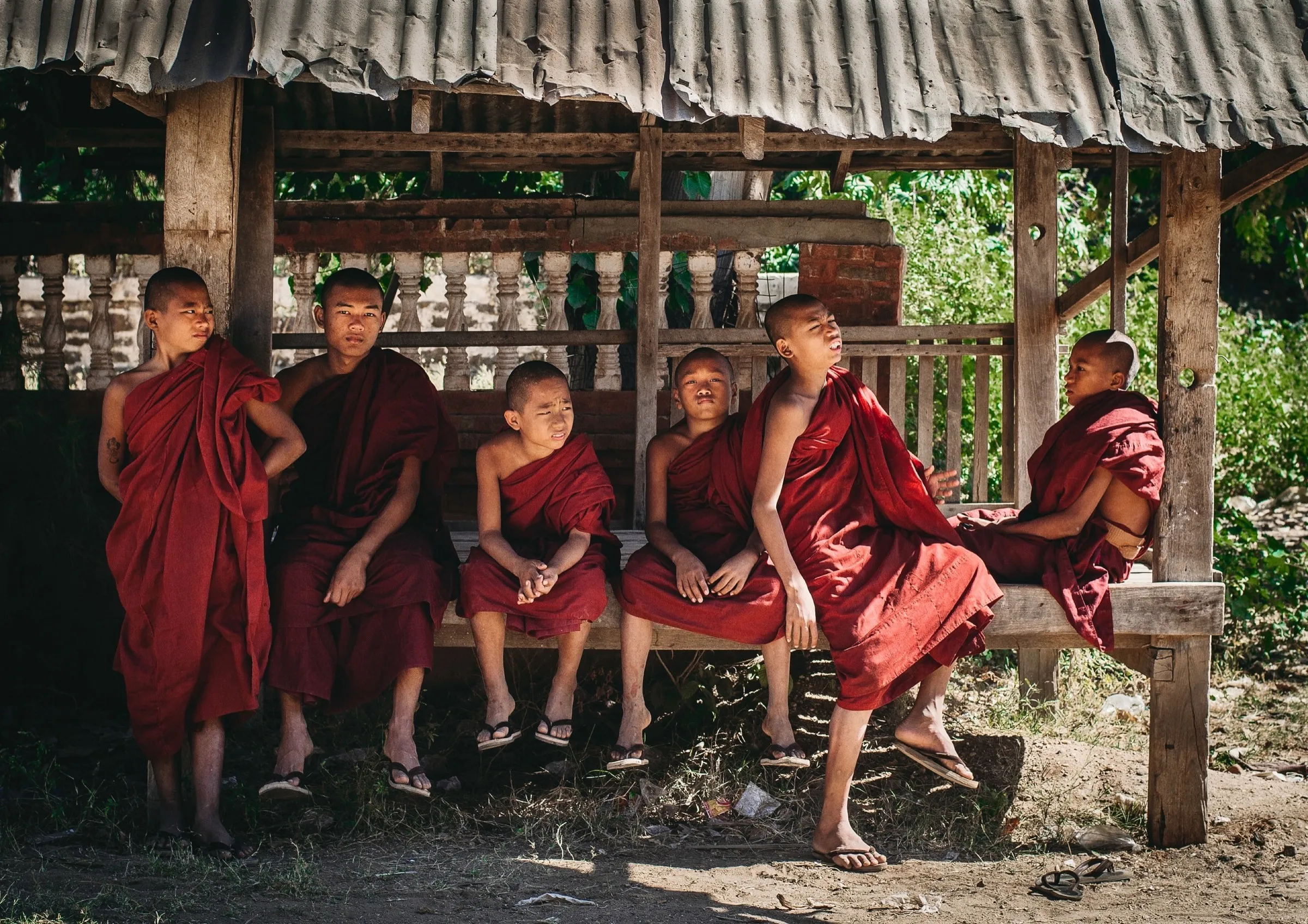 A row of young monks in crimson robes on a bench